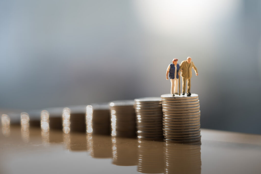 Miniature people: Old couple figure standing on top of coin stack. Mega backdoor Roth IRA