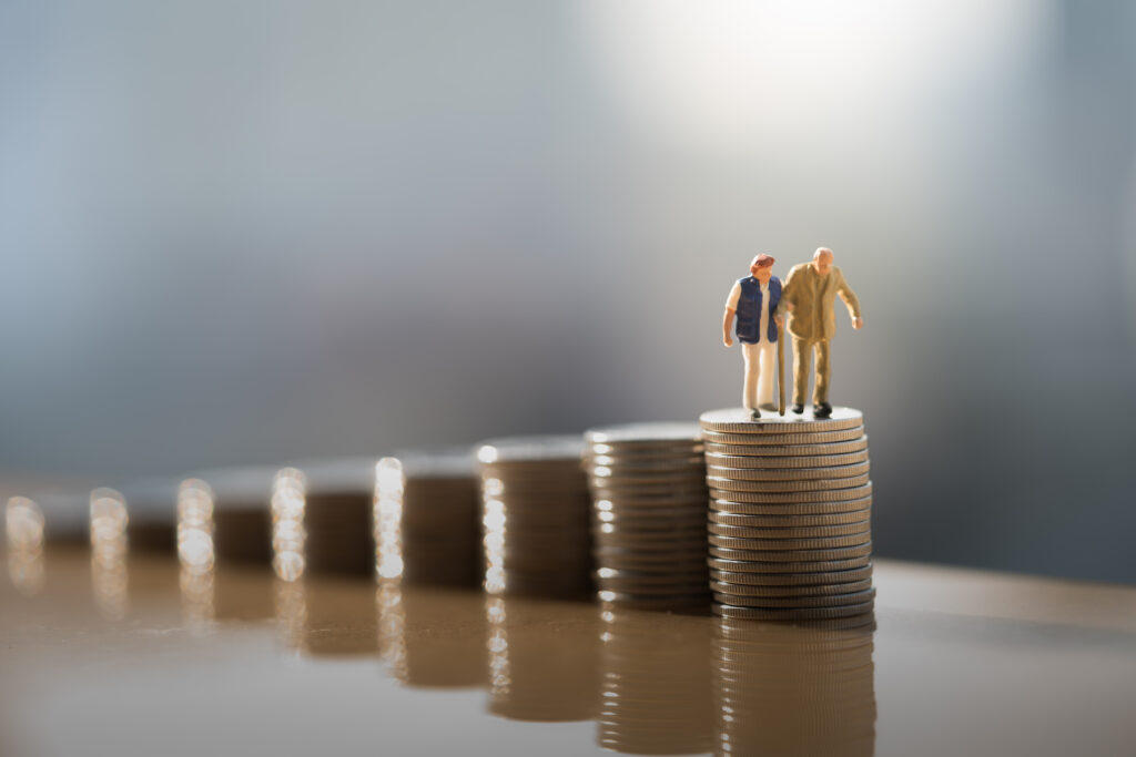 miniature people: old couple figure standing on top of coin stack. mega backdoor roth ira