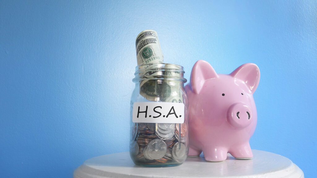 a pink piggy bank sitting next to a jar filled with money